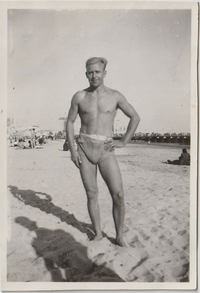 Man in belted swimsuit identified on verso as "Claude Leslie" in a contrapposto position.