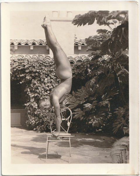 Vintage physique photo Unidentified model shows off his strength and skill by balancing on a wrought iron chair.