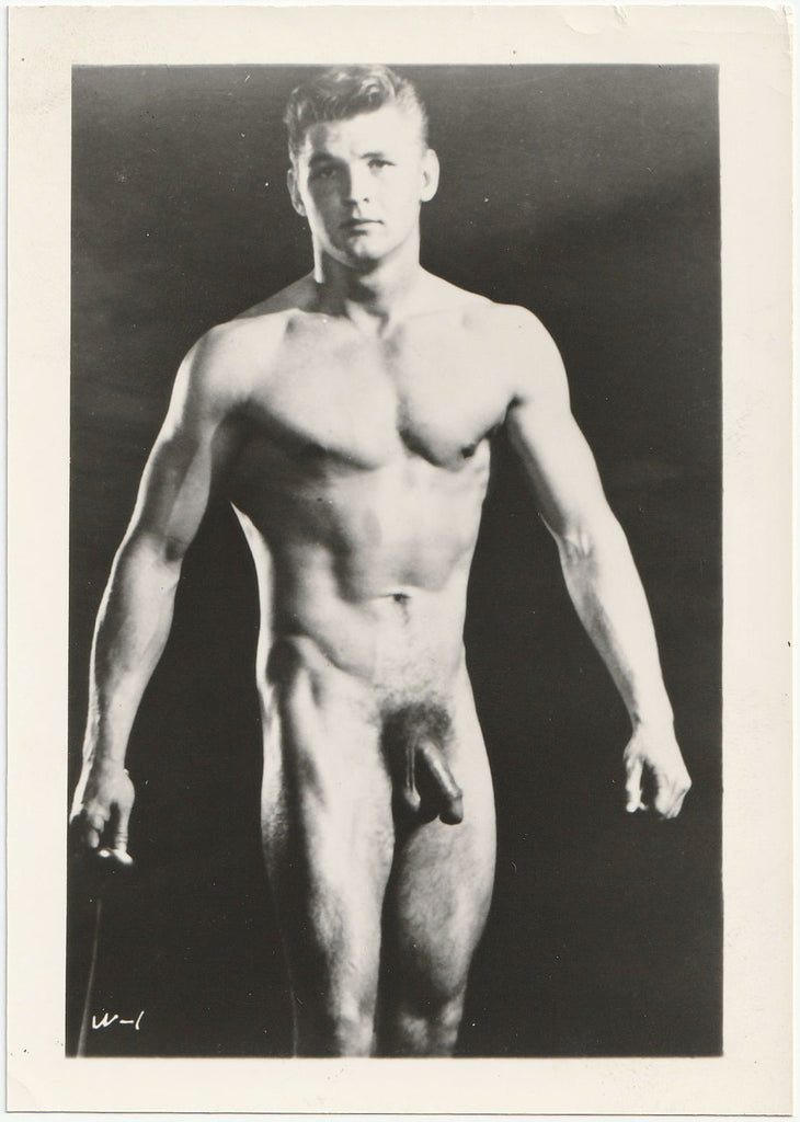 Muscular and handsome guy stands as if his lats prevent his arms from getting close to his body vintage male nude photo.