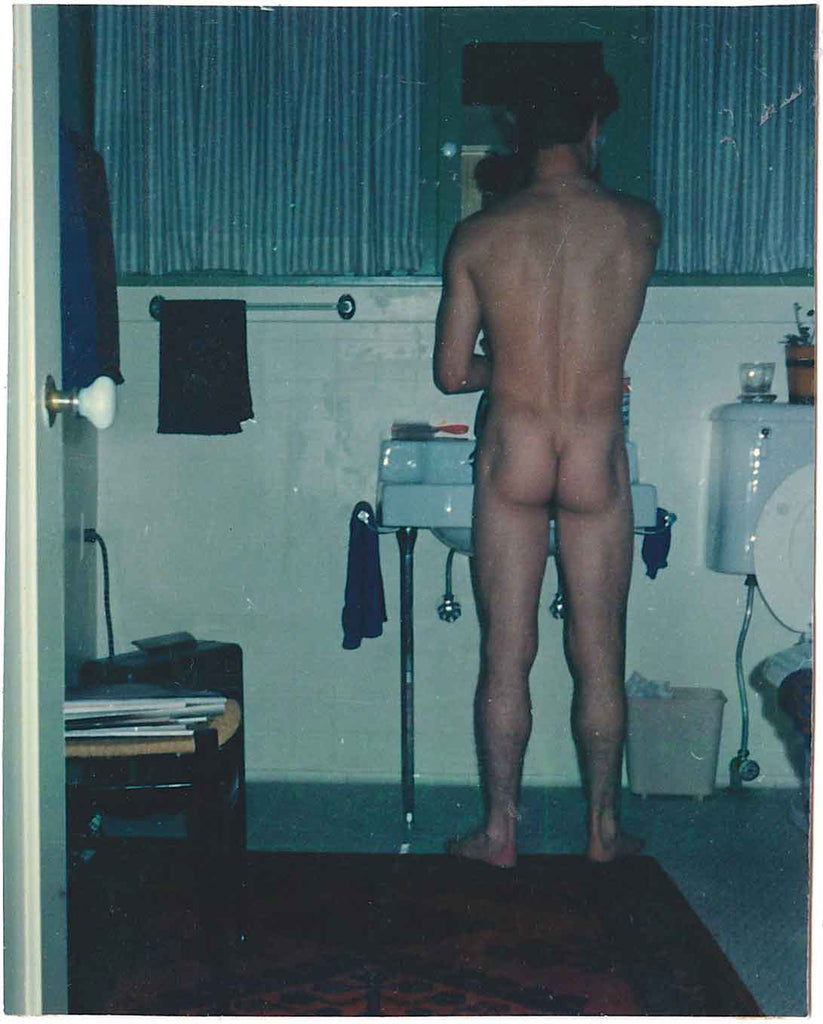 Nude standing at the bathroom sink shaving. vintage color photo