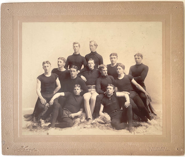 Large format photo of 12 members of an unidentified team relaxing on (wolfskin?) rugs, San Francisco, 1890s.