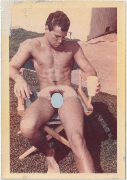 Original vintage gay color photo of a handsome model seated in a director's chair,