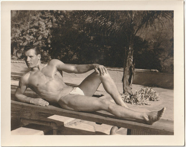 Vintage gay physique photo of handsome broad-shouldered guy in posing strap on a diving board.