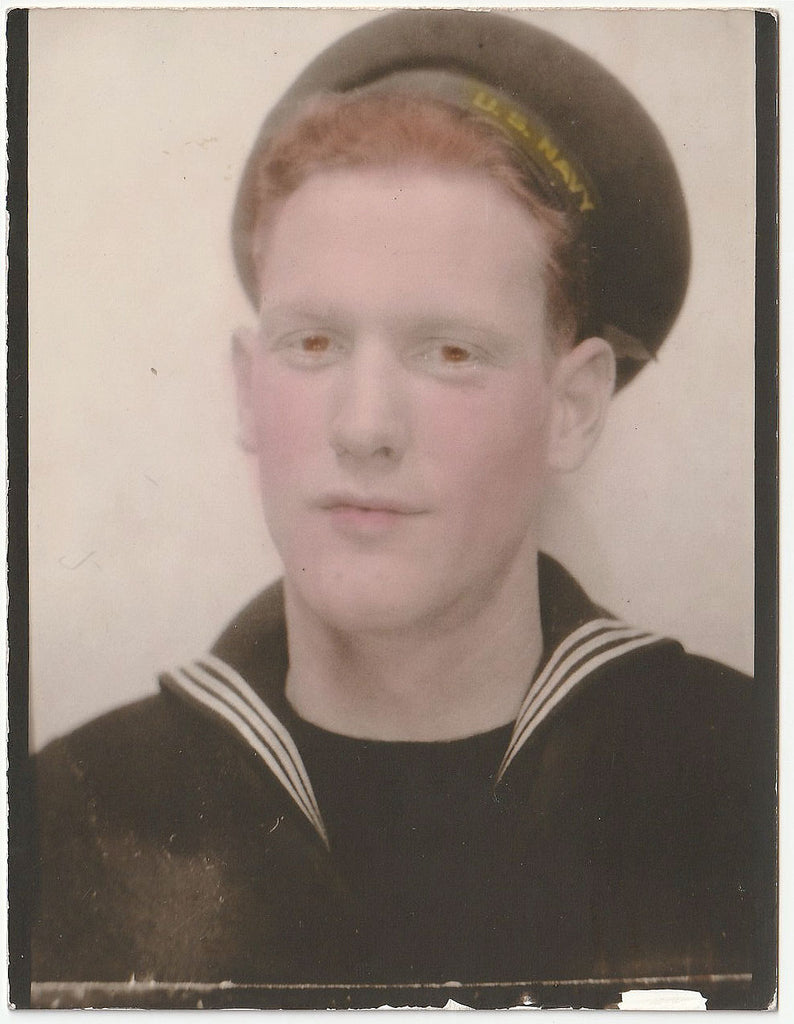 A vintage portrait of a young man in a U.S. Navy uniform wearing a cap.