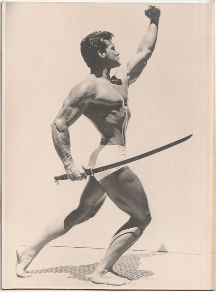 Vintage photo by an unidentified photographer shows Steve Reeves raising a fist and holding a sword as he lunges forward.