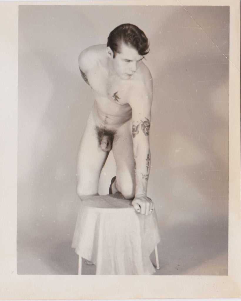Vintage gay photo Handsome young man with tattoos scattered on his chest and arms