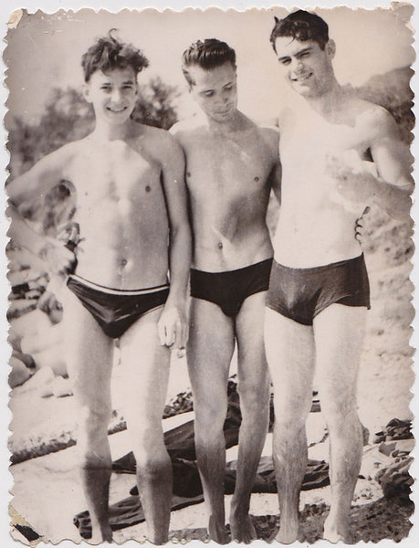 vintage photo Three cute young guys stand close together at the beach.