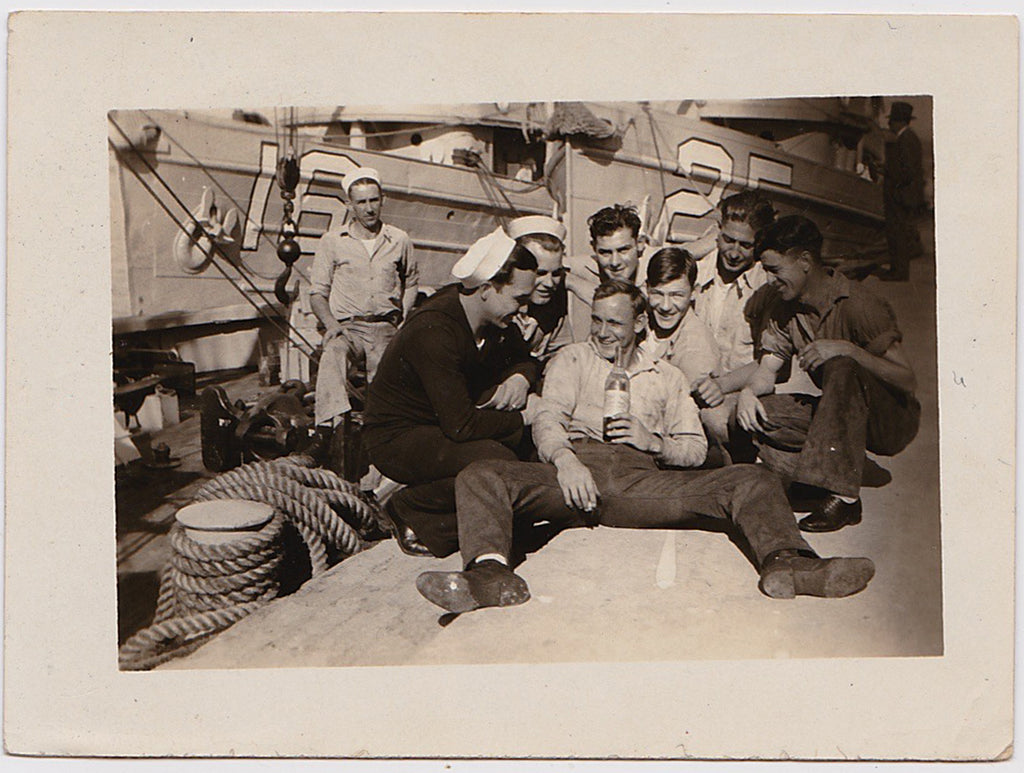 Six good looking sailors surround their clearly inebriated buddy seated on the dock vintage photo