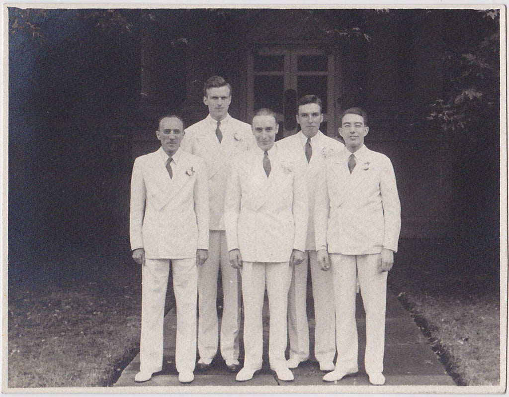 Five dapper gents in white suits with double-breasted jackets and a boutonniere, vintage snapshot