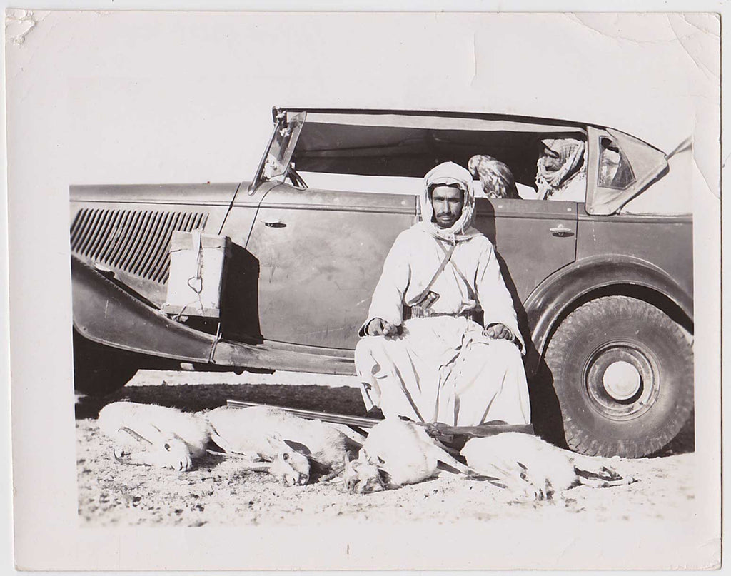 photo of Khamis ibn Mohammed Rimthan posing with a rifle on his lap and four gazelles at his feet. 