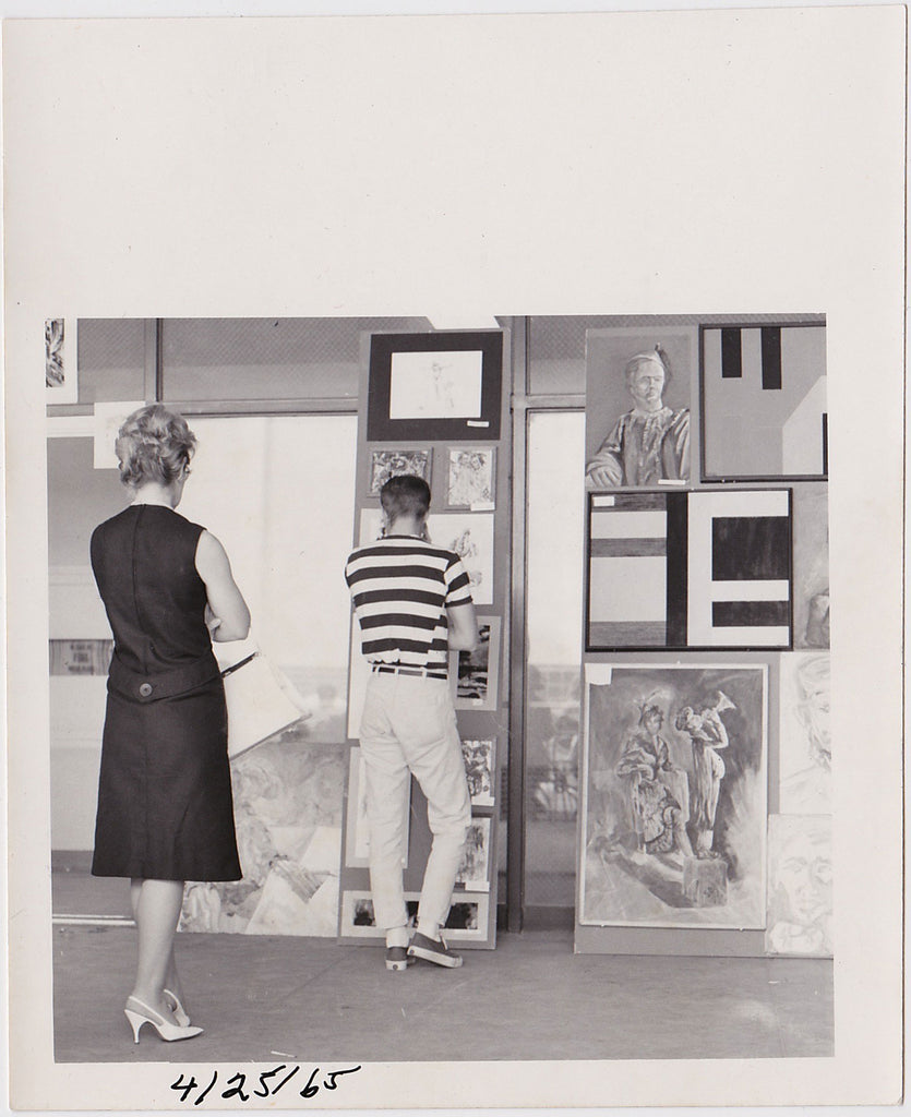 Young man looking at art. Older woman looking at young man, or so it seems.  Vintage photo 1965
