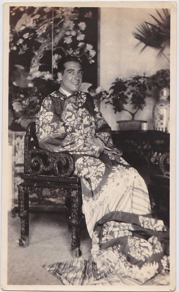 Man wearing an extraordinary Chinese robe, surrounded by art and furnishings vintage photo