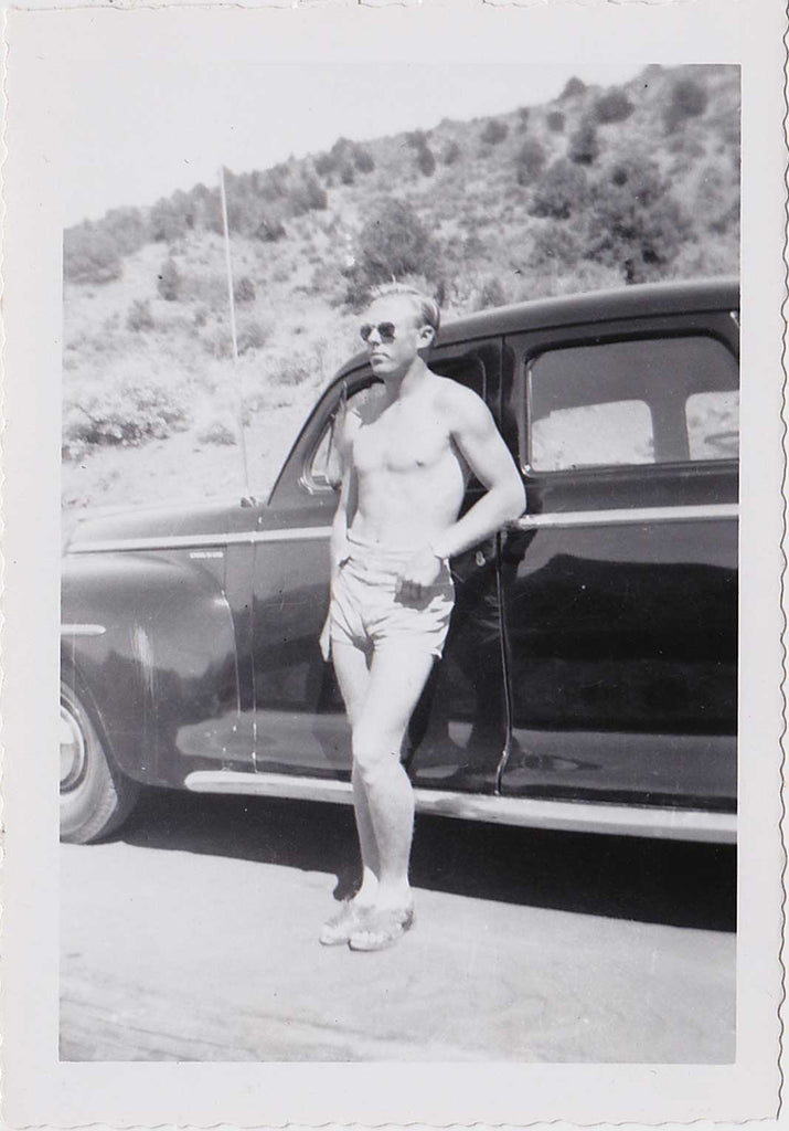 Handsome blond guy with sunglasses poses with a certain nonchalance in his short shorts and sandals. Vintage gay snapshot