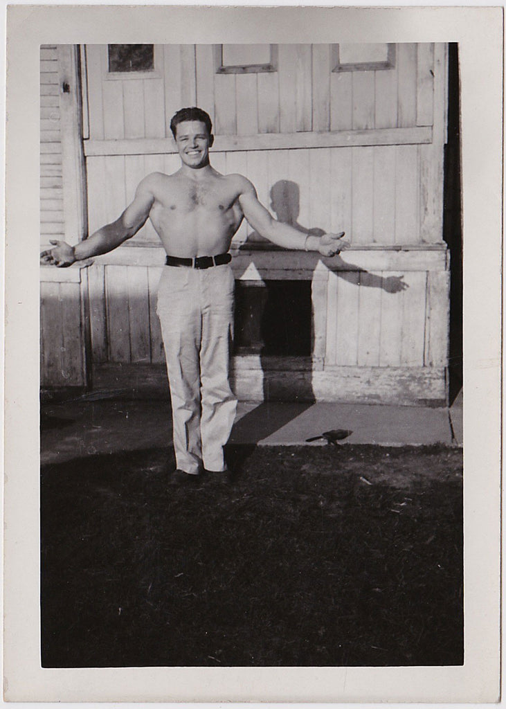 handsome, smiling bodybuilder flexing with his shirt off vintage photo