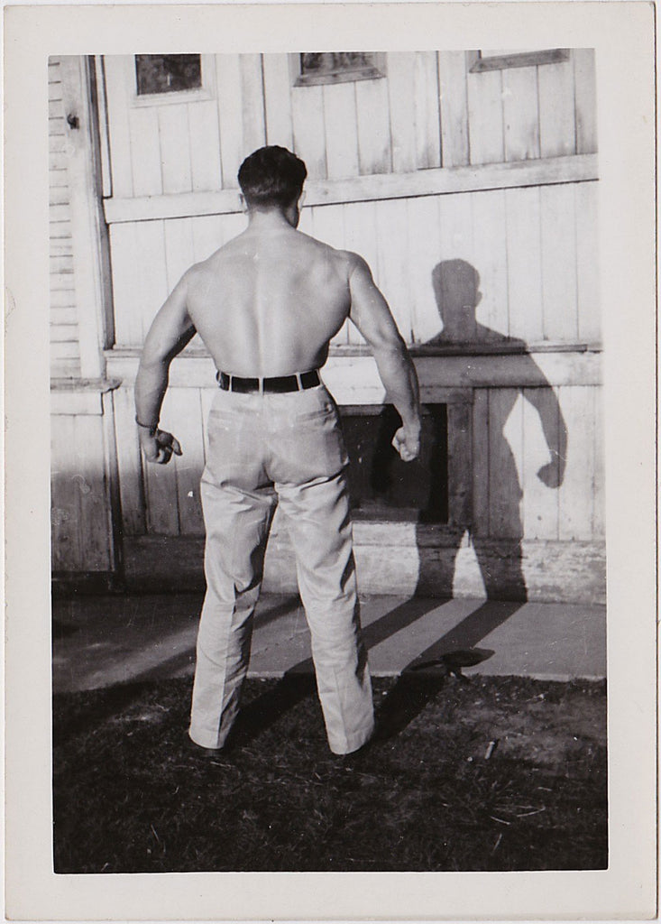 handsome bodybuilder flexing his massive back with his shirt off vintage photo