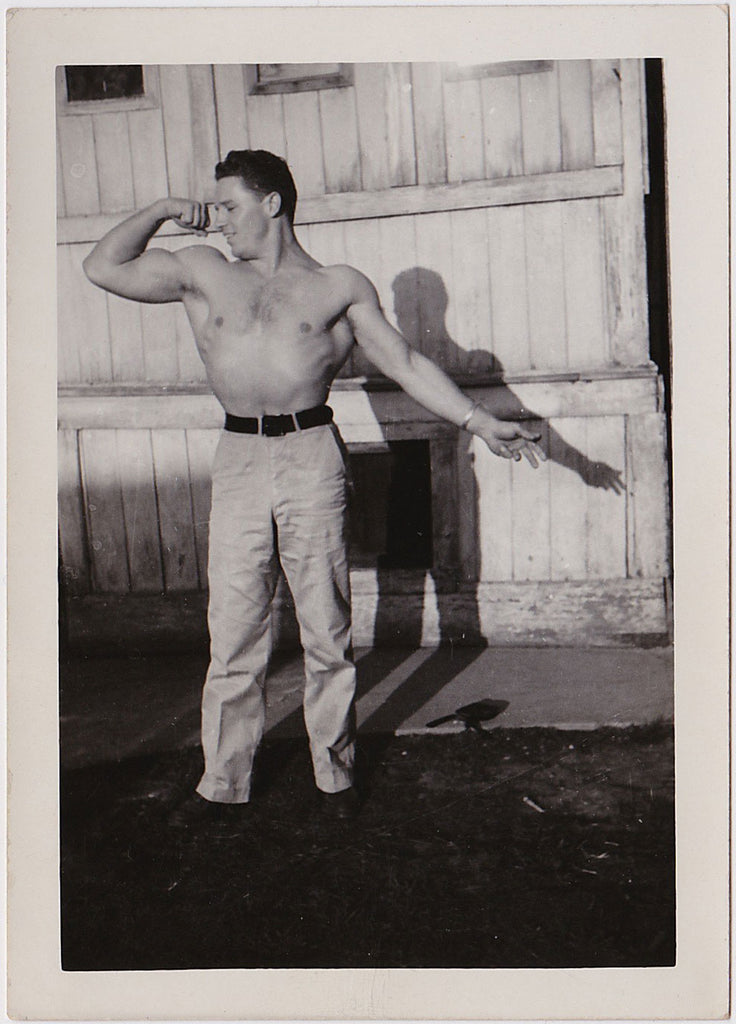handsome, smiling bodybuilder flexing his bicep vintage photo