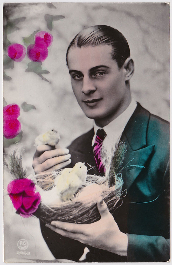 Handsome guy with slicked-back hair holds a basket with baby chicks. Hand colored photo postcard