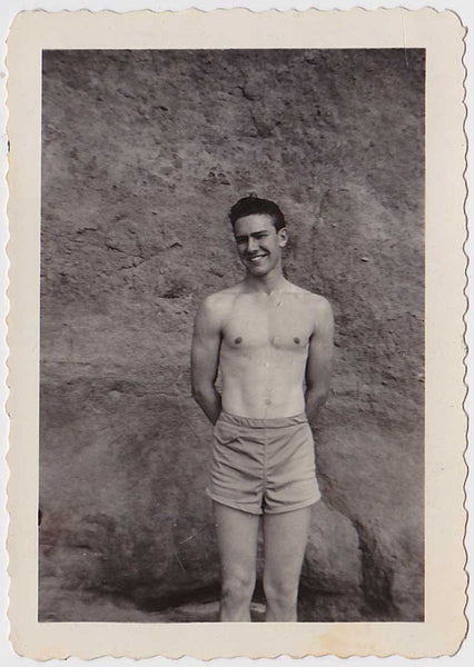 Handsome young guy with an engaging smile stands with his hands behind his back. vintage gay snapshot