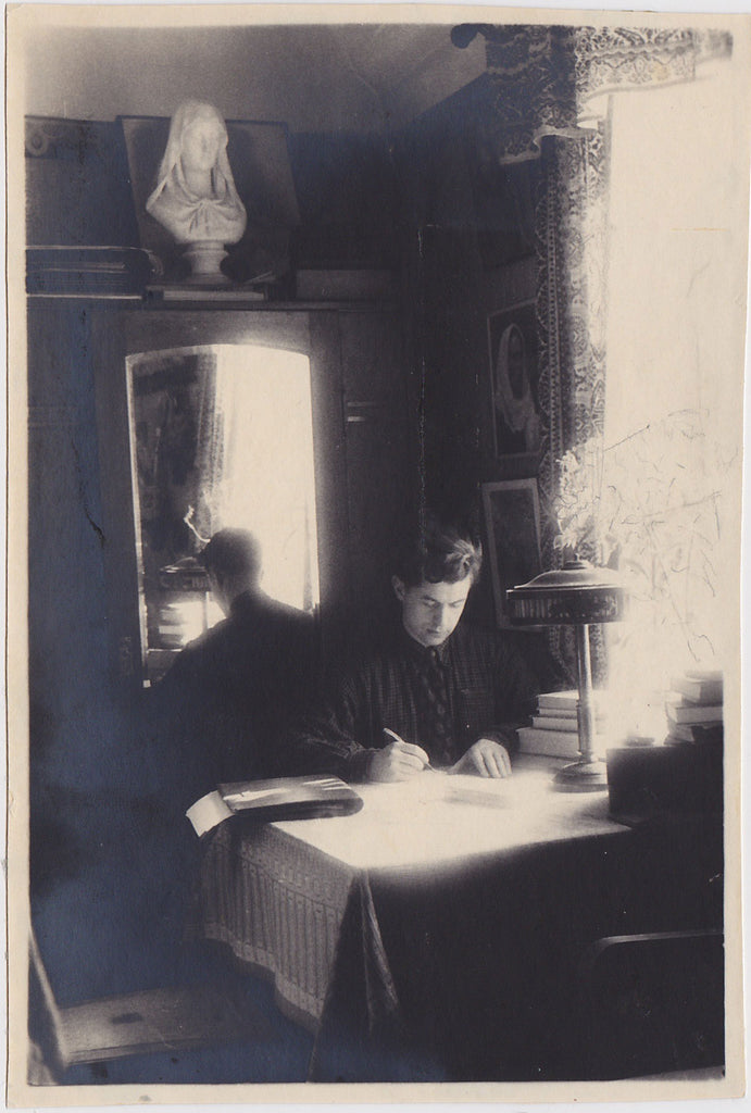 Beautifully composed vintage photo of a handsome young man seated at a table with pen in hand