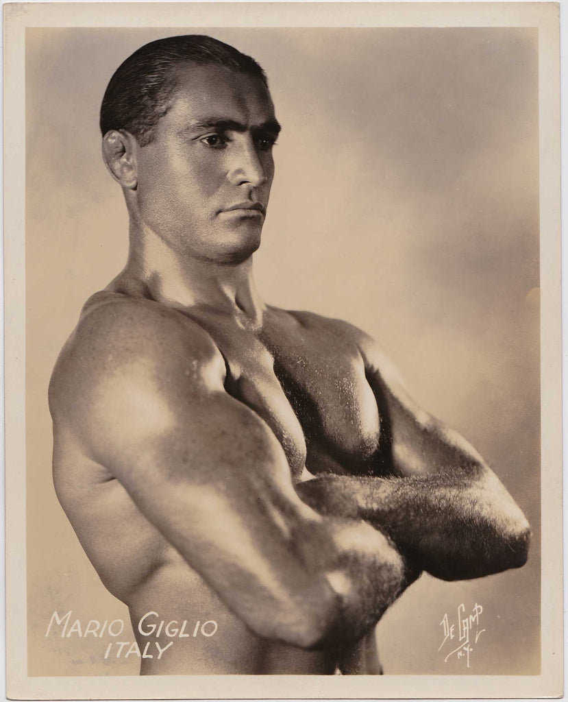 Handsome Italian wrestler Mario Giglio with arms folded across his chest. Vintage photo by De Camp Studio, New York