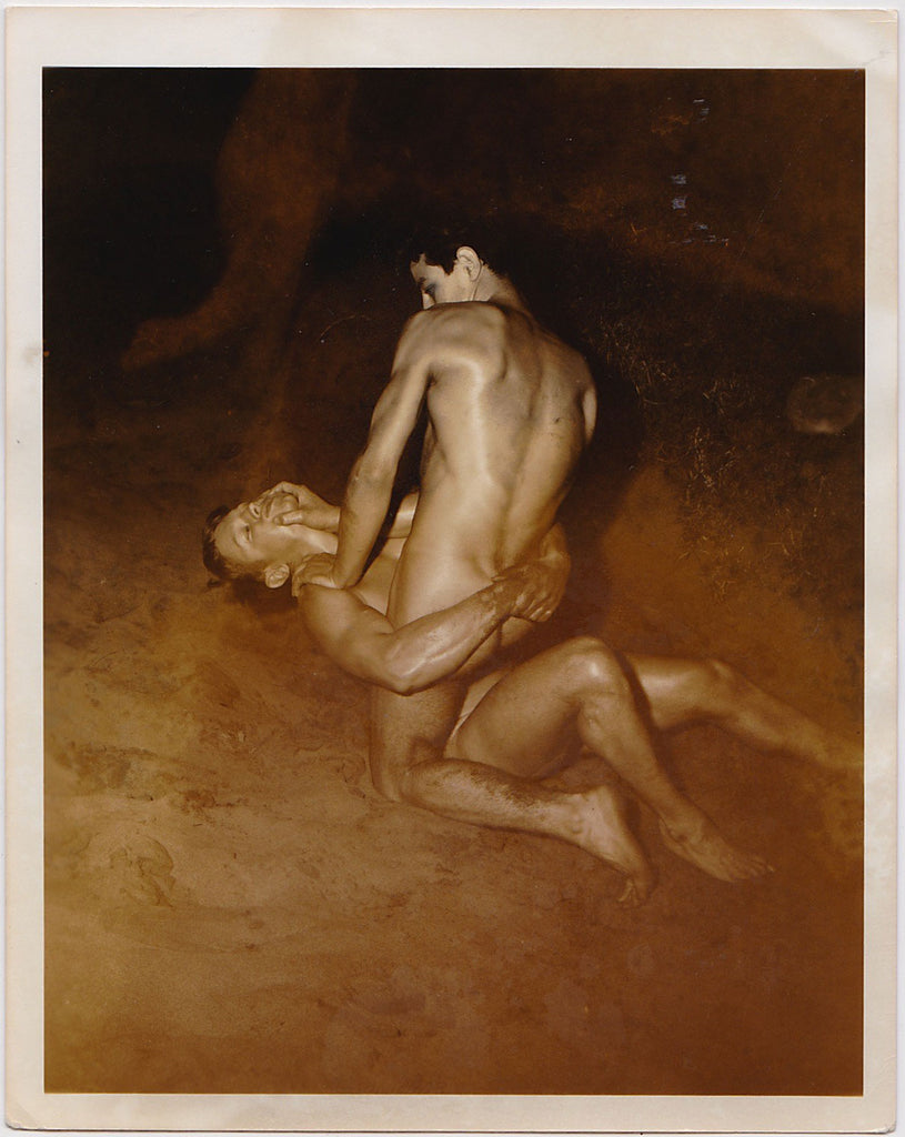 Two handsome young nude models wrestle in the sand in this rare night-time shot