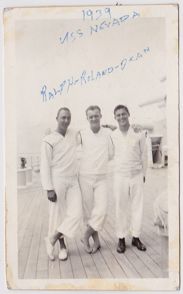 These affectionate sailors identified as Ralph, Roland and Dean, stand on the deck of the USS Nevada. Unusual assortment of footwear.