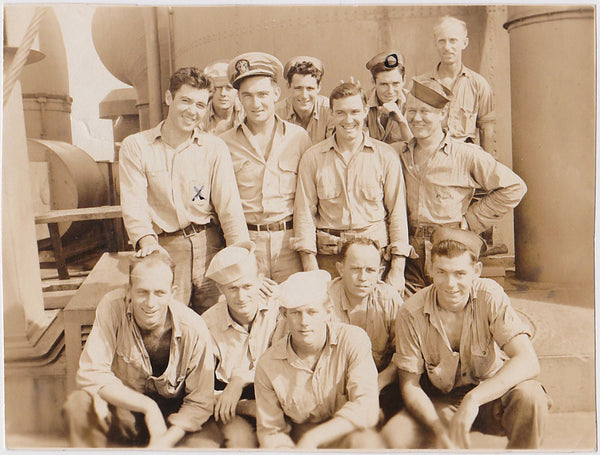 13 sailors crowd in for a group photo, seemingly relaxed and smiling. 