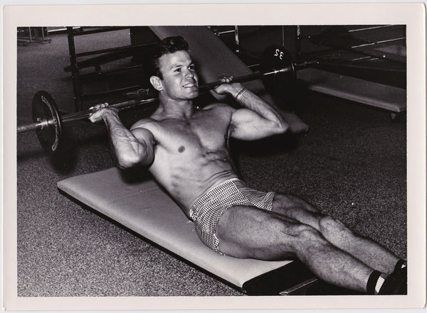 Handsome and muscular young bodybuilder works his abs in this rare vintage gay image by Swan Photo,