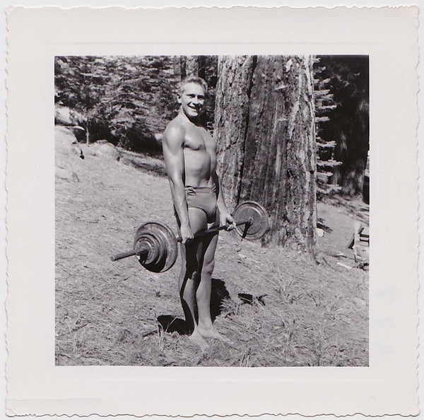 Handsome bodybuilder lifting weights on a hill, vintage photo